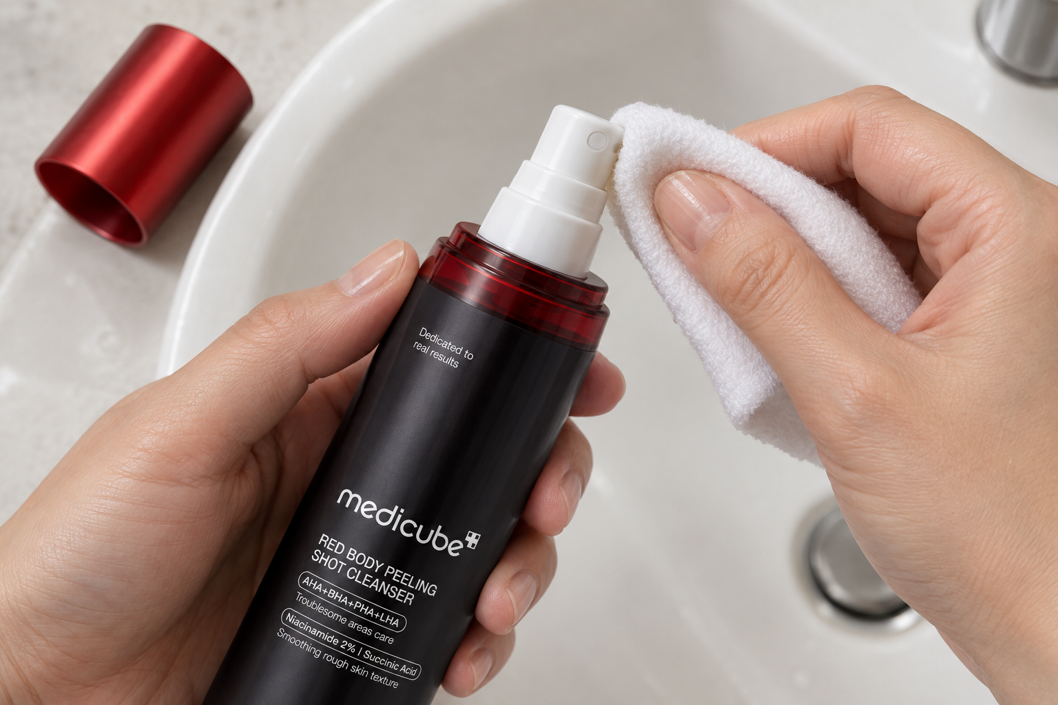 Detalle del pulverizador blanco de Medicube Red Body Peeling Shot mientras se limpia suavemente su exterior