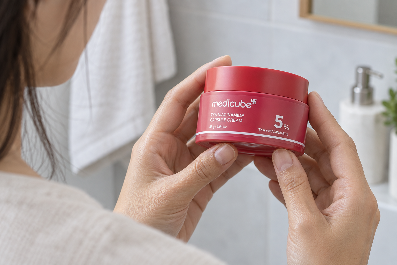 Manos sosteniendo la crema TXA Niacinamide de Medicube para leer el nombre y el 5 % del frontal